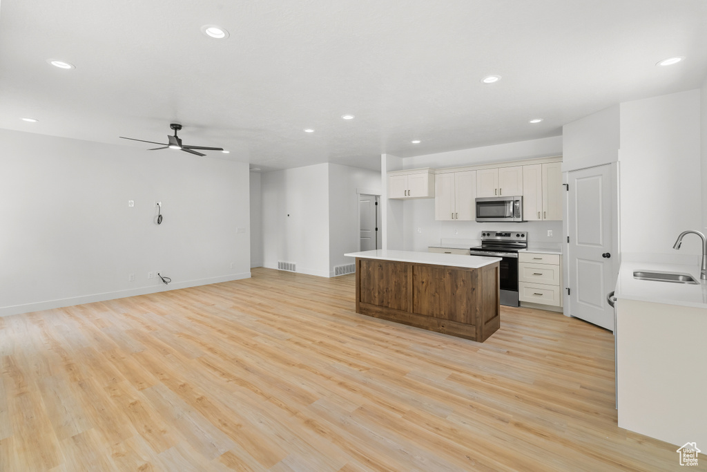 Kitchen with stainless steel appliances, a center island, recessed lighting, light wood-style floors, and light countertops