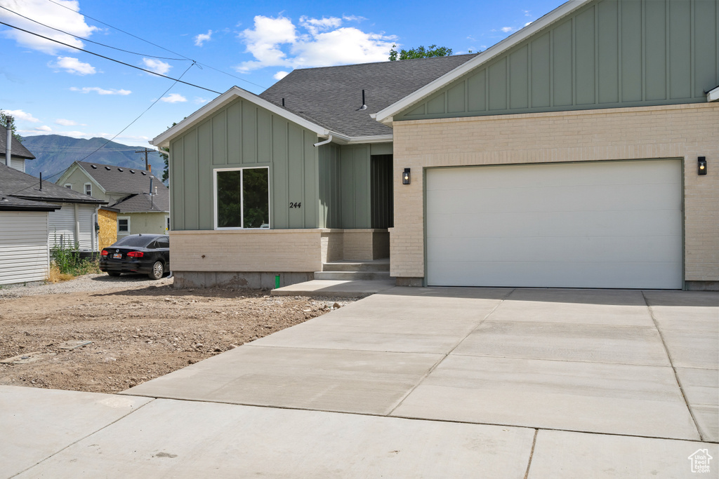 View of front facade with board and batten siding, brick siding, and concrete driveway