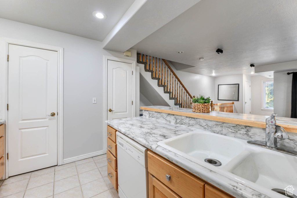 Kitchen with white dishwasher, light tile patterned floors, light countertops, and recessed lighting