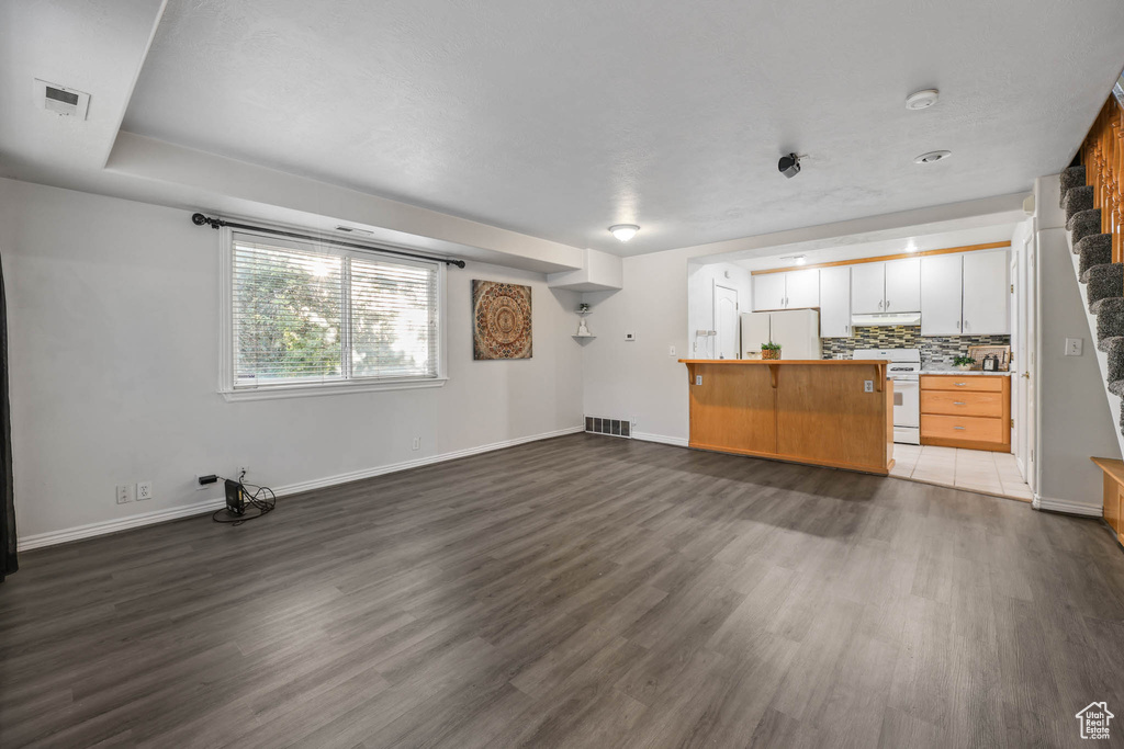 Unfurnished living room with dark wood-style flooring and baseboards