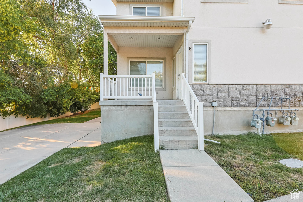 Property entrance featuring stucco siding, a porch, and a yard