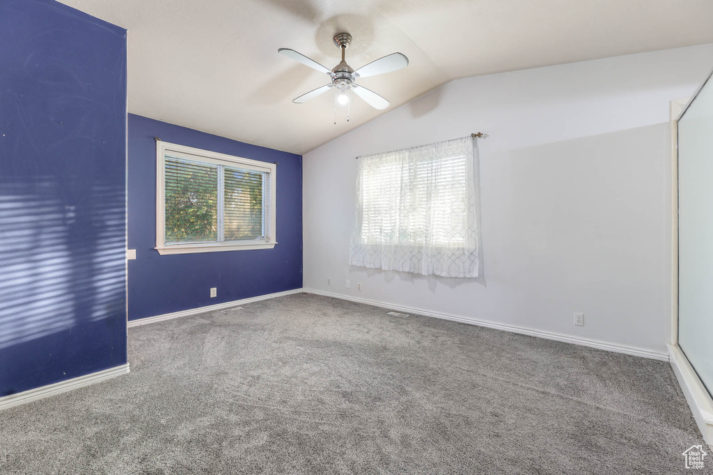 Empty room featuring carpet flooring, ceiling fan, and lofted ceiling