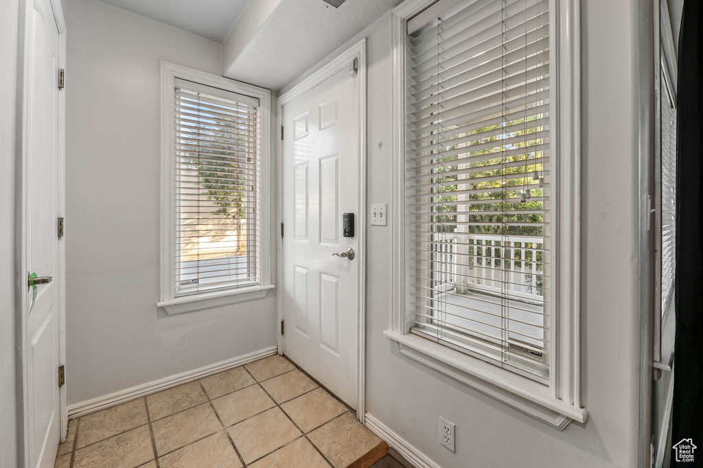 Doorway to outside featuring baseboards and light tile patterned floors