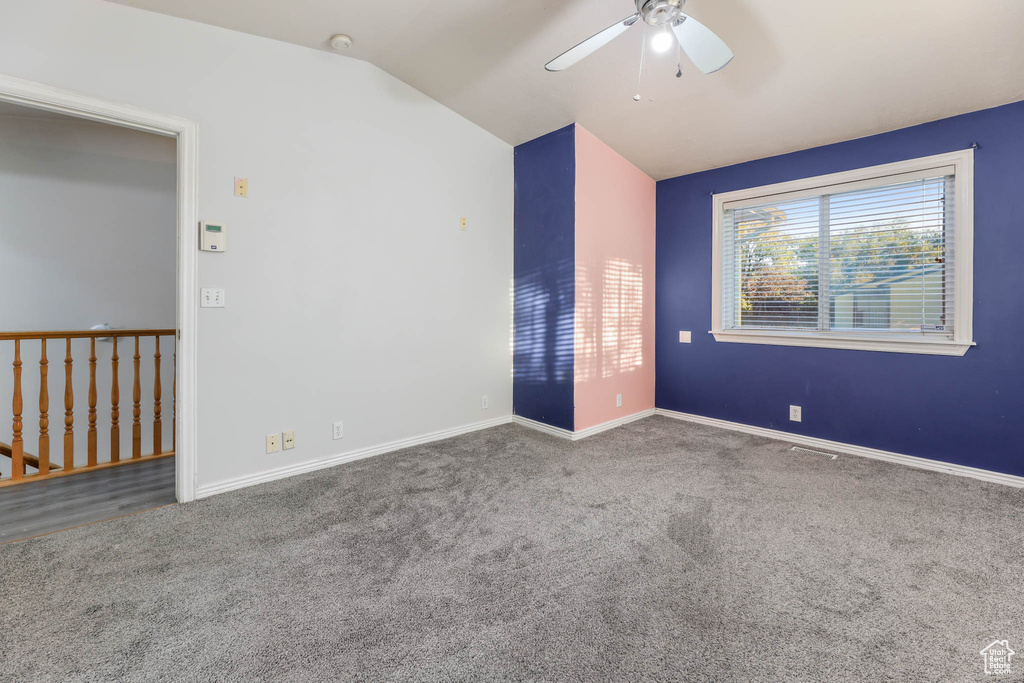 Carpeted spare room with ceiling fan, vaulted ceiling, and a smoke detector