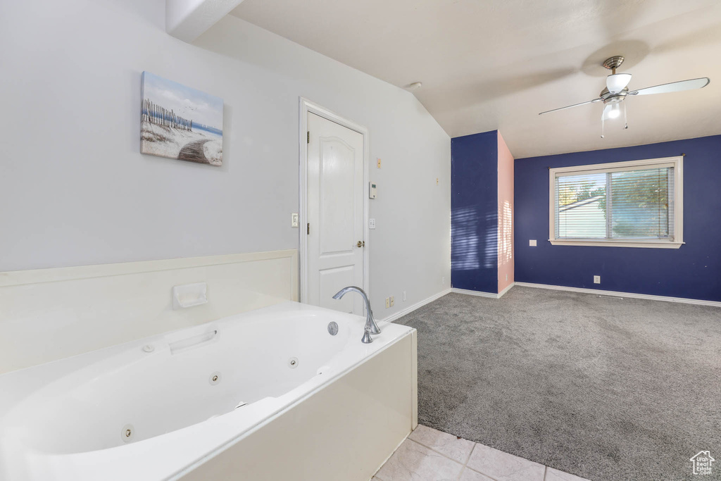 Bathroom with a jetted tub, ceiling fan, and vaulted ceiling