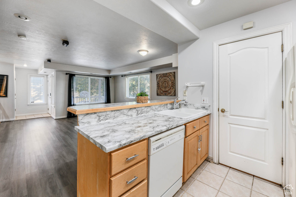 Kitchen featuring white dishwasher, a peninsula, open floor plan, light wood-style flooring, and recessed lighting