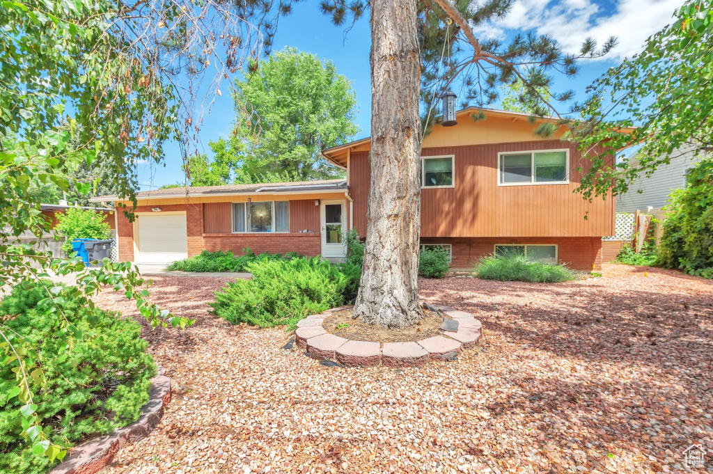 Split level home featuring an attached garage and brick siding