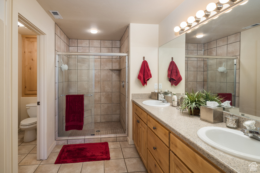 Bathroom featuring double vanity, a stall shower, and tile patterned floors