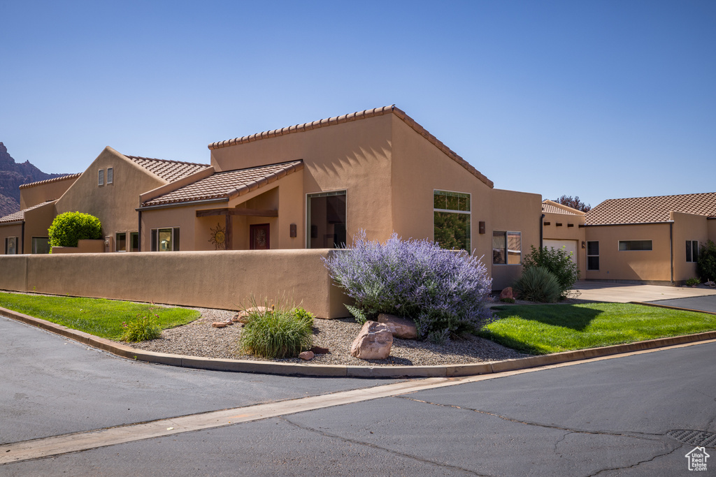 View of front facade featuring stucco siding, concrete driveway, an attached garage, and a tiled roof
