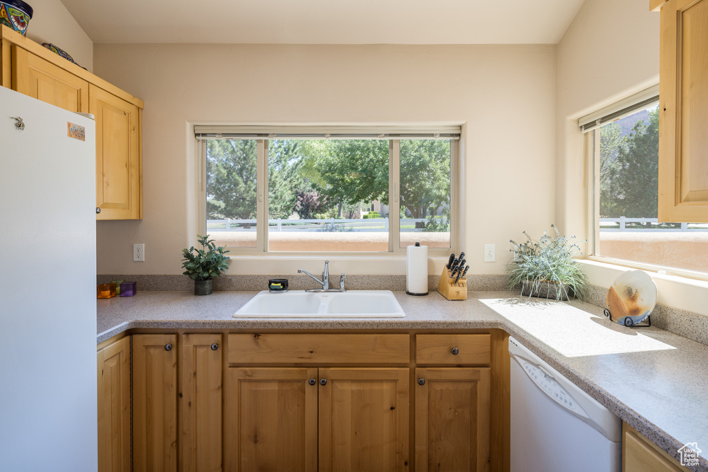 Kitchen featuring white appliances, light countertops, and light brown cabinets