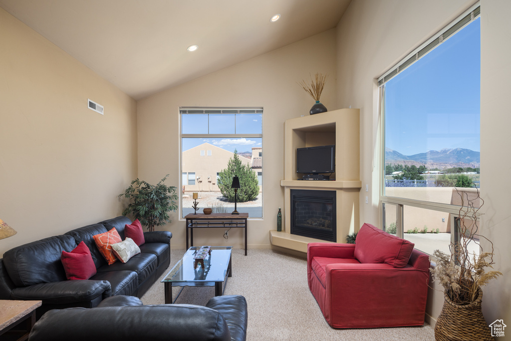 Carpeted living room with a glass covered fireplace, lofted ceiling, and recessed lighting