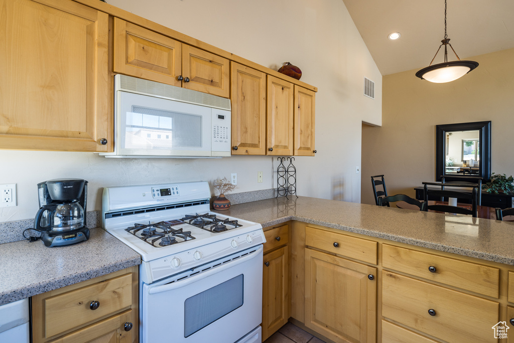 Kitchen with white appliances, lofted ceiling, light brown cabinetry, a peninsula, and recessed lighting