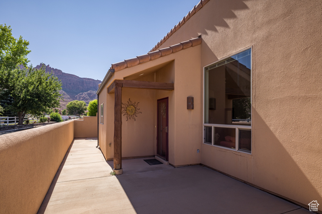 View of exterior entry featuring stucco siding, a mountain view, a patio, and a tiled roof