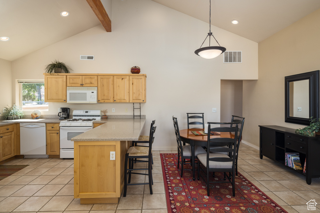 Kitchen with white appliances, high vaulted ceiling, light brown cabinetry, a peninsula, and a kitchen breakfast bar