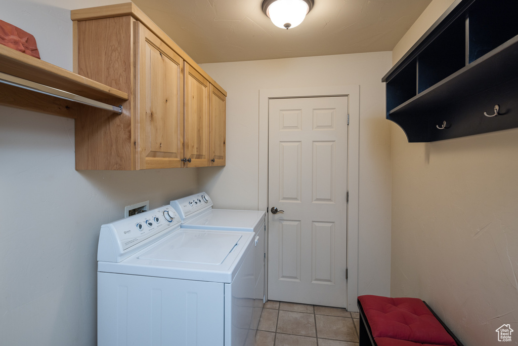 Laundry area with independent washer and dryer, cabinet space, and light tile patterned floors