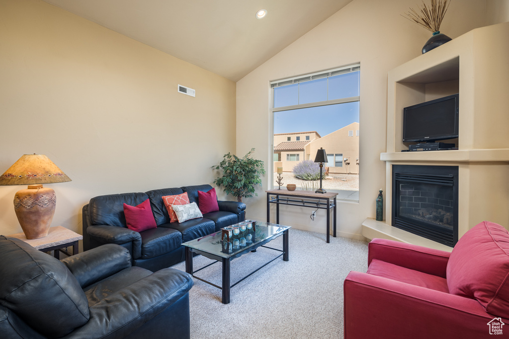 Carpeted living room with high vaulted ceiling and a glass covered fireplace