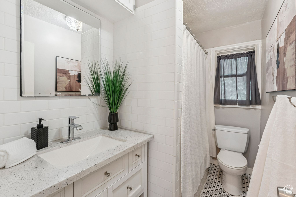 Bathroom with vanity, tile walls, a textured ceiling, backsplash, and tile patterned floors