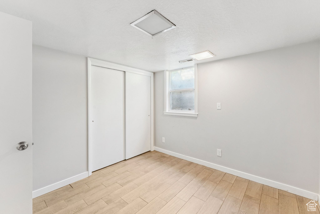 Unfurnished bedroom with light wood-style floors and a closet