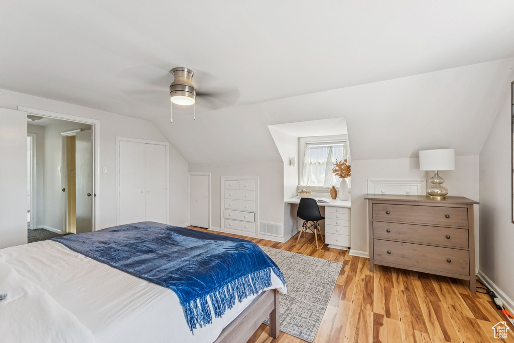 Bedroom with vaulted ceiling, wood finished floors, an office area, and ceiling fan