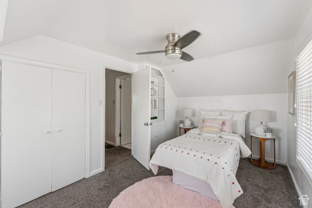 Carpeted bedroom with vaulted ceiling, multiple windows, ceiling fan, and a closet