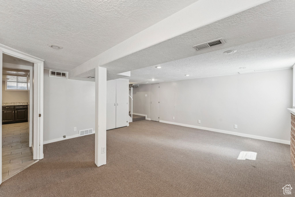 Below grade area with carpet floors, a textured ceiling, and recessed lighting