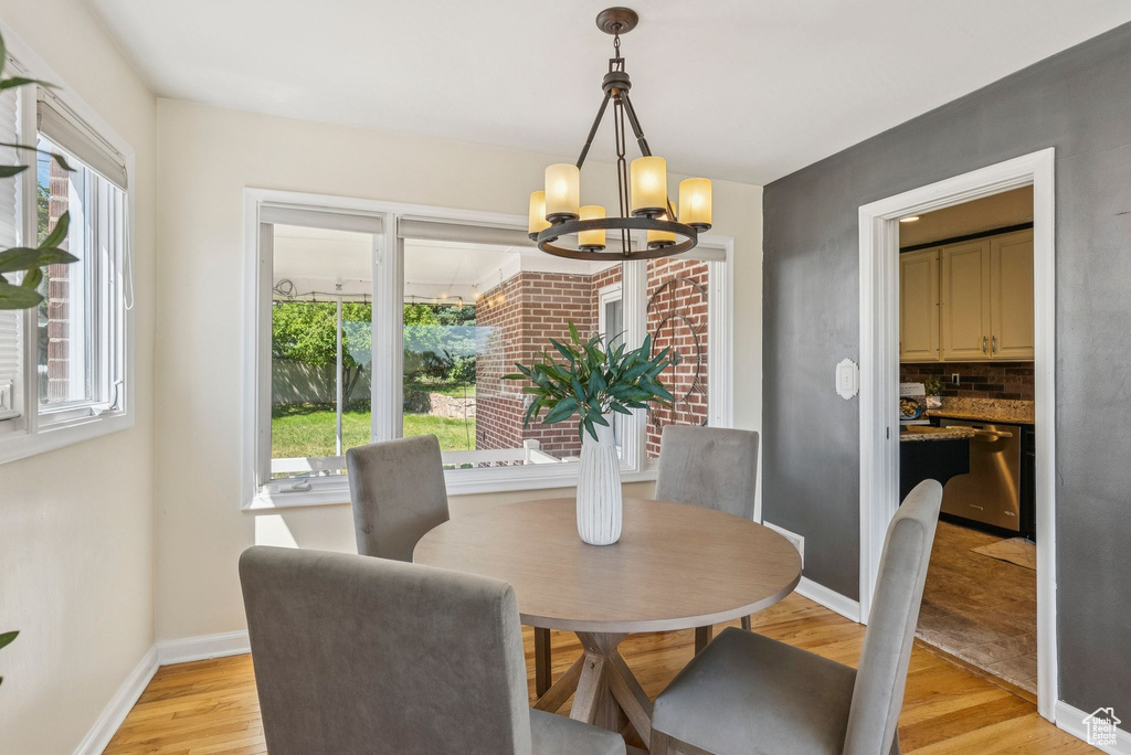 Dining space with a chandelier, healthy amount of natural light, and light wood finished floors