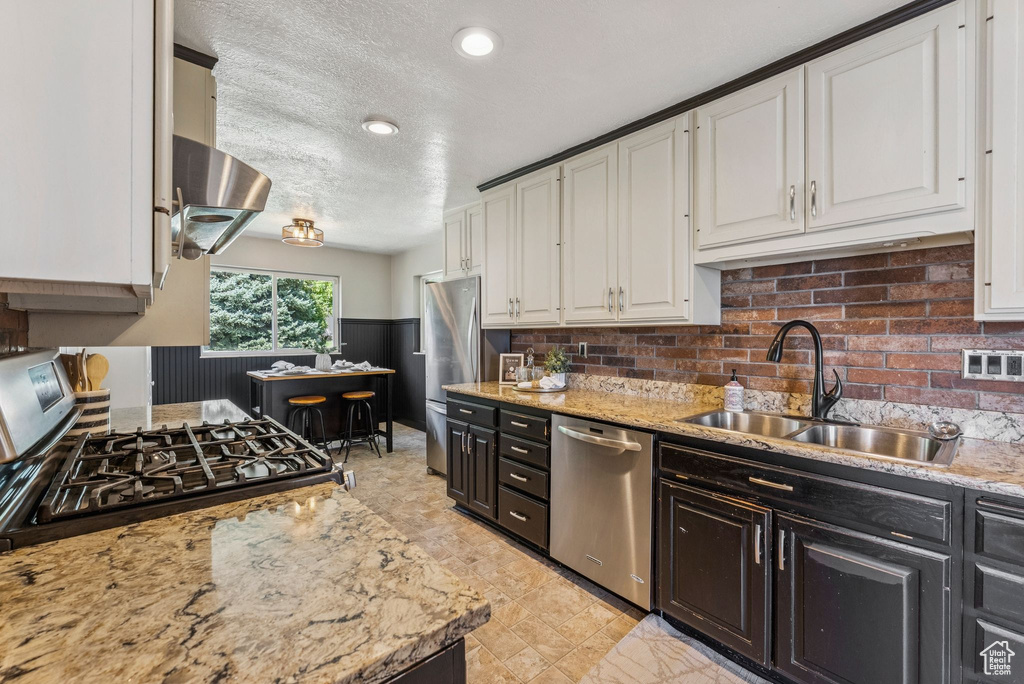 Kitchen with stainless steel appliances, white cabinets, dark cabinetry, a textured ceiling, and recessed lighting