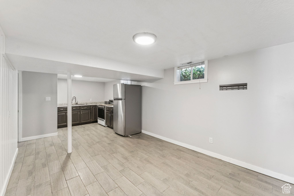 Kitchen with freestanding refrigerator, light countertops, light wood finished floors, white range, and dark brown cabinetry