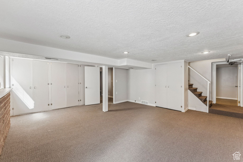 Finished basement with stairway, a textured ceiling, carpet, and recessed lighting