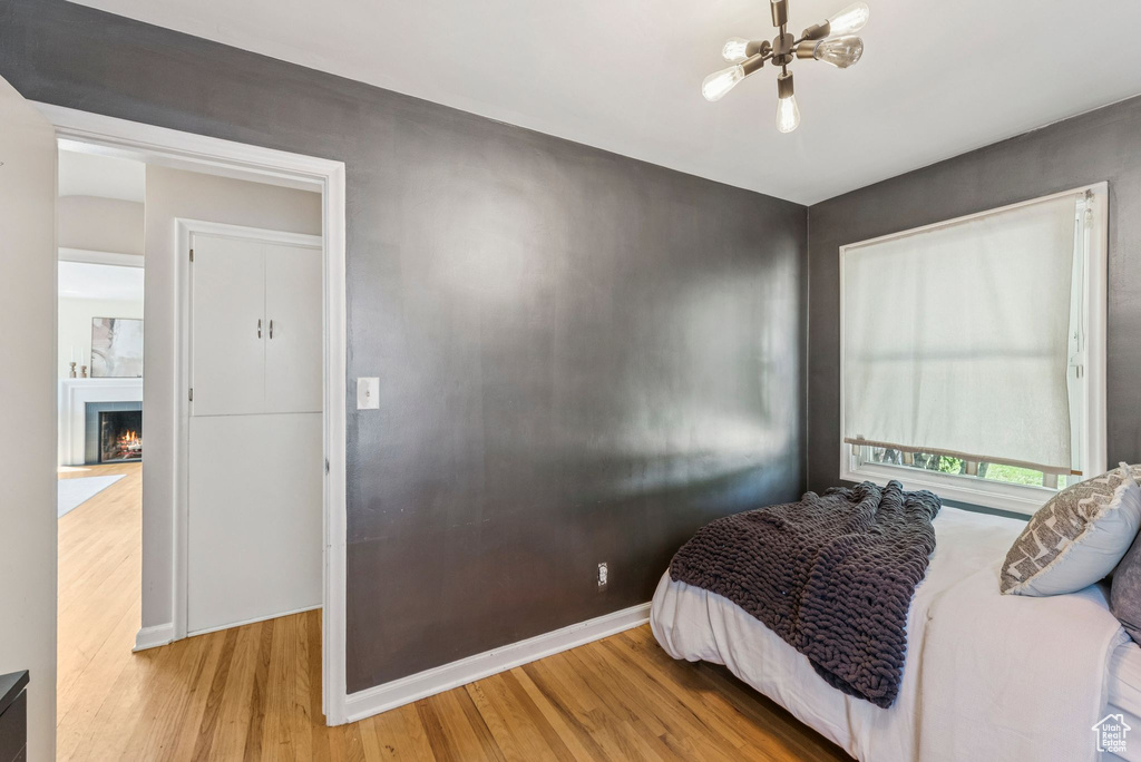 Bedroom with wood finished floors and a lit fireplace
