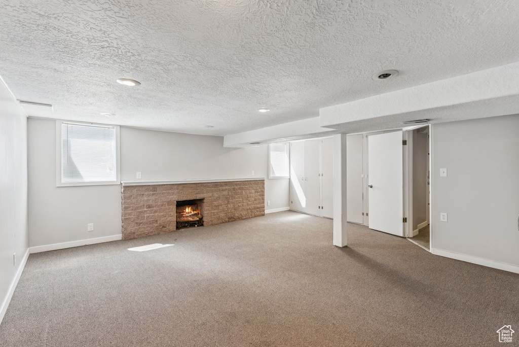 Below grade area with a fireplace, carpet, a textured ceiling, and plenty of natural light