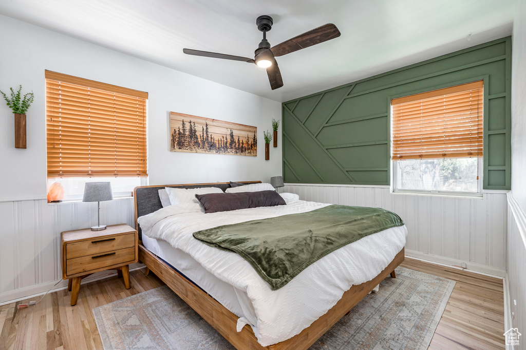 Bedroom featuring wood finished floors, wainscoting, and a ceiling fan