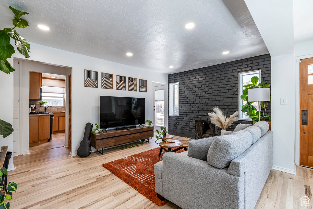 Living room with light wood-style floors, recessed lighting, and a fireplace