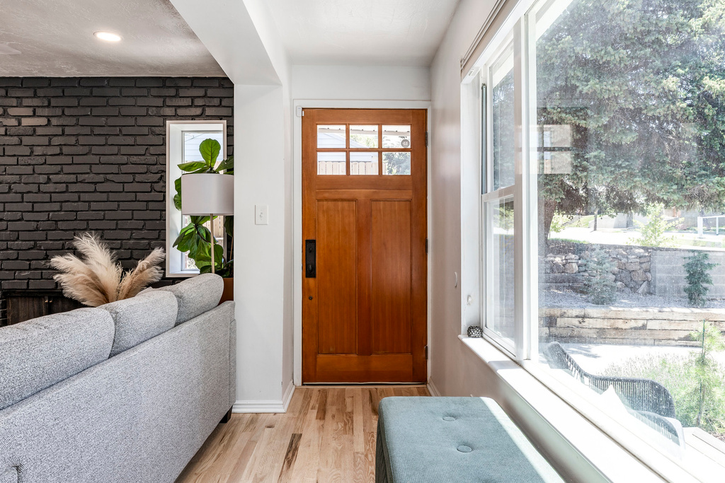 Foyer entrance with light wood-style floors and brick wall
