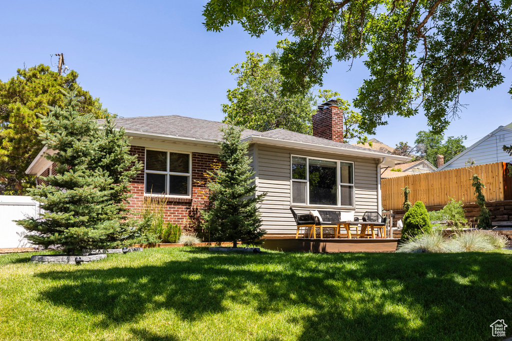 Back of property with a chimney and a shingled roof