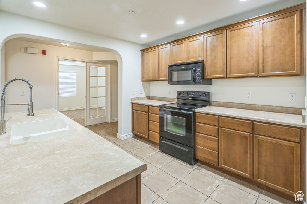 Kitchen with black appliances, arched walkways, light tile patterned floors, light countertops, and recessed lighting