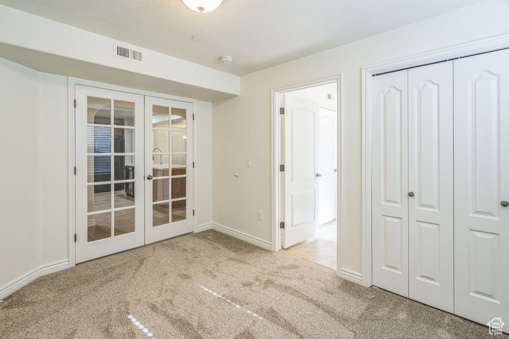Unfurnished bedroom with french doors, carpet flooring, and a closet