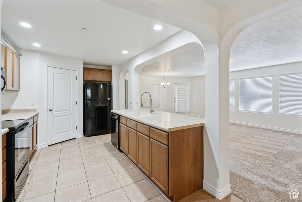 Kitchen with black appliances, arched walkways, light countertops, brown cabinets, and recessed lighting