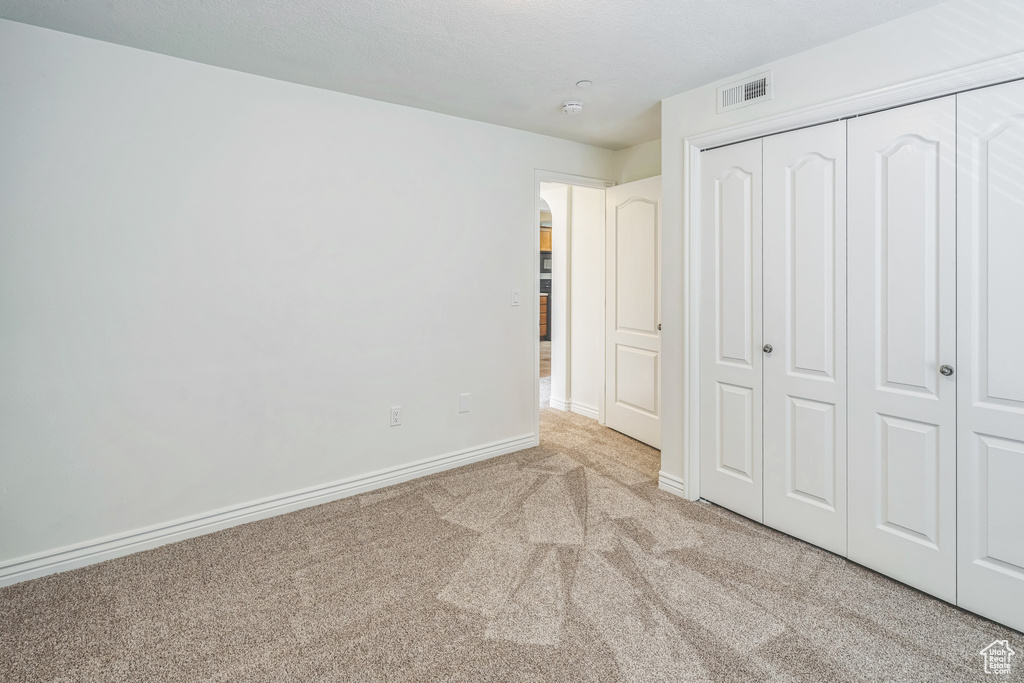 Unfurnished bedroom featuring carpet flooring, arched walkways, and a closet