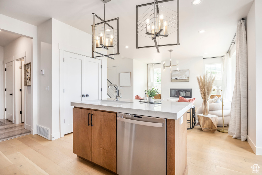 Kitchen with stainless steel dishwasher, light wood-style flooring, a chandelier, brown cabinetry, and recessed lighting