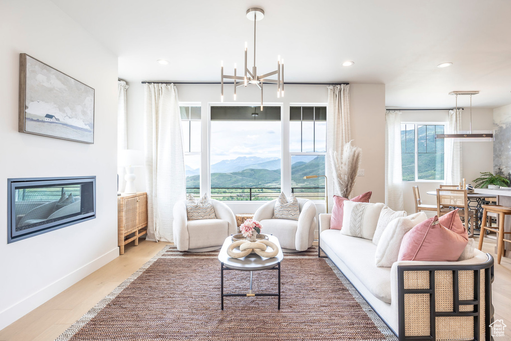 Living area featuring a mountain view, a chandelier, wood finished floors, recessed lighting, and a glass covered fireplace