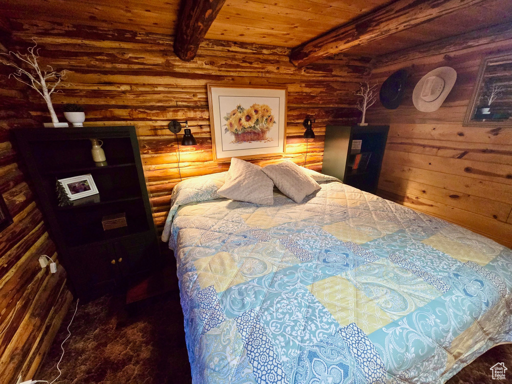 Bedroom featuring log walls and a wood ceiling with exposed beams
