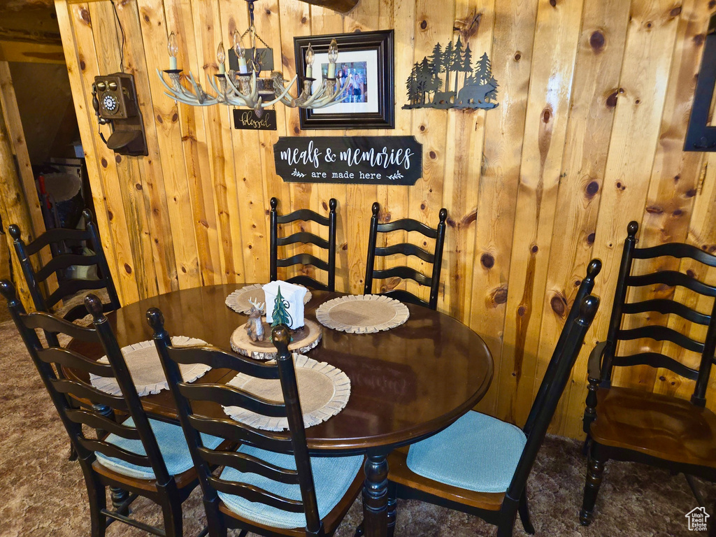 Dining area featuring wooden walls and a chandelier