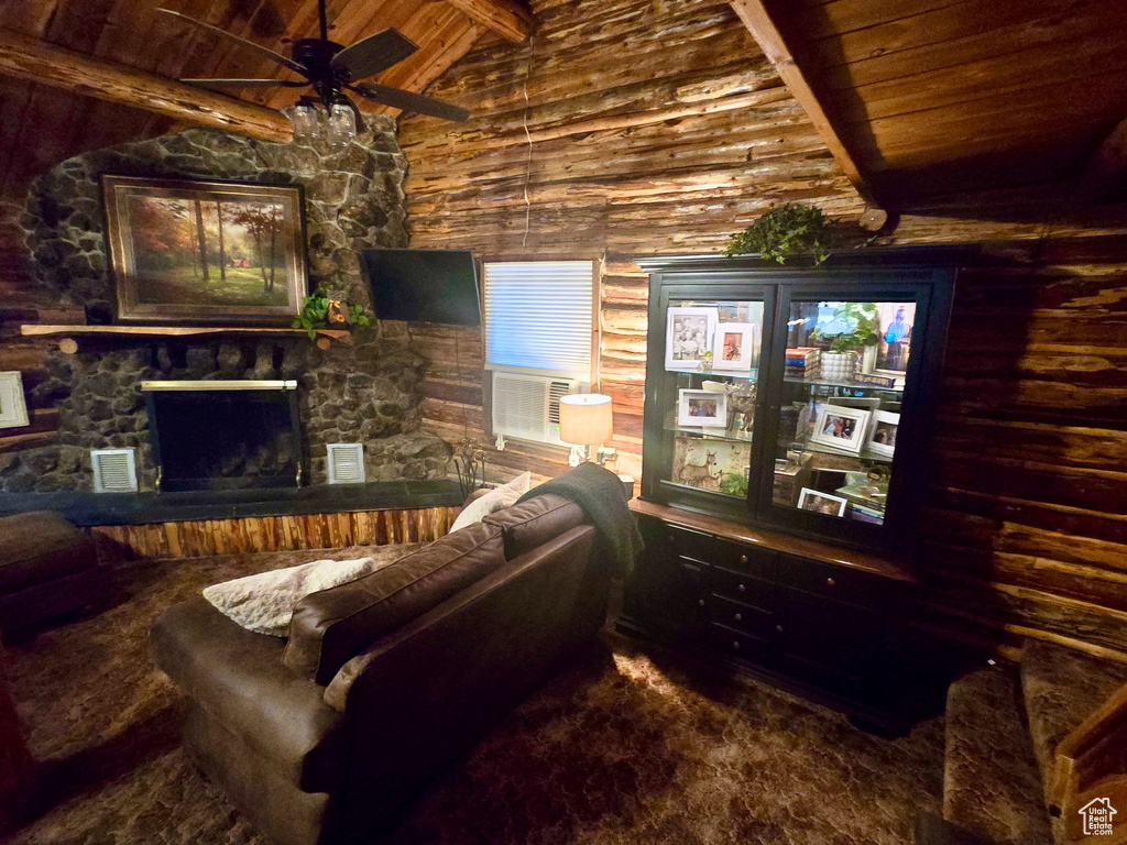 Living area with wood ceiling, a ceiling fan, a stone fireplace, and wood walls