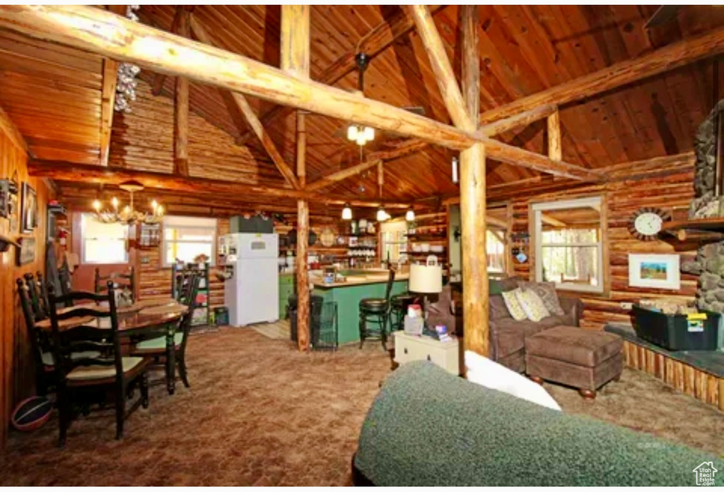 Living area featuring plenty of natural light, carpet flooring, a wood ceiling with exposed beams, a chandelier, and log walls