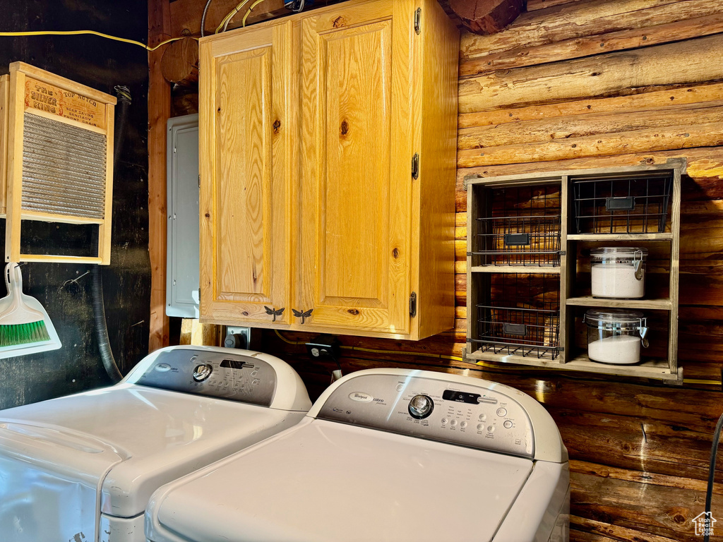 Washroom with washer and clothes dryer, cabinet space, rustic walls, and electric panel