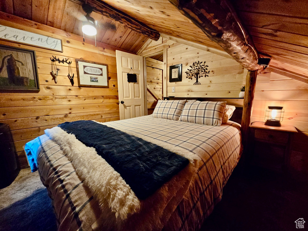 Bedroom with wood walls, wooden ceiling, and carpet floors
