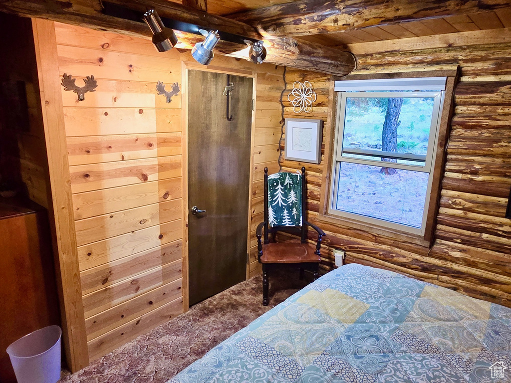 Bedroom featuring log walls, a wood ceiling with exposed beams, and wooden walls