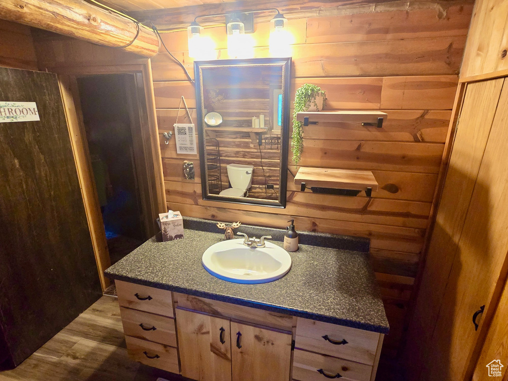 Bathroom featuring wooden walls, vanity, and wood finished floors