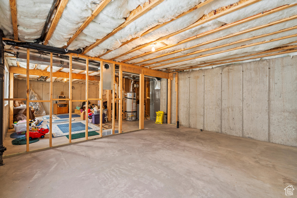 Unfinished below grade area featuring strapped water heater and heating unit
